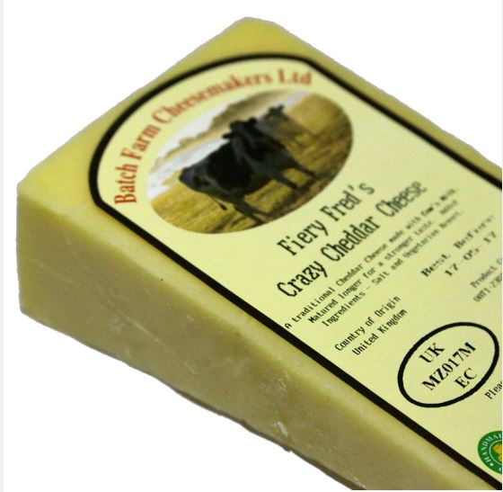 A slice of Farmhouse Fiery Fred Cheddar cheese wrapped in paper with a label on top, placed against a white background.